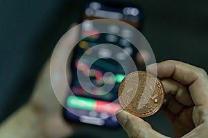 Woman holding a bitcoin coin while trading on the other hand