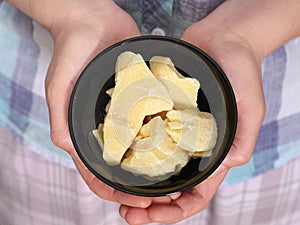 A woman holding a black bowl with organic cocoa butter in it in her hands