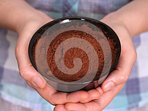 A woman holding a black bowl with organic cocoa powder in it in her hands