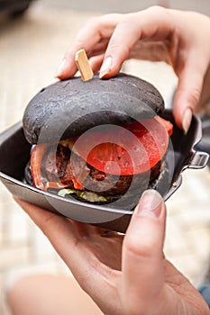 Woman holding black burger with marbled beef