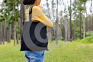 woman holding black cotton bag in nature