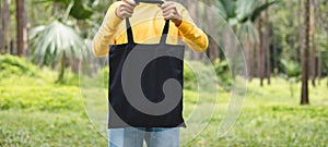 woman holding black cotton bag in nature background