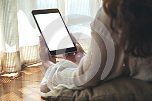 A woman holding black tablet pc with blank white desktop screen while laying down on the floor with feeling