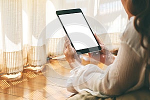 A woman holding black tablet pc with blank white desktop screen while laying down on the floor with feeling