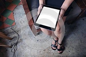 Woman holding black tablet pc with blank white desktop screen while sitting in cafe