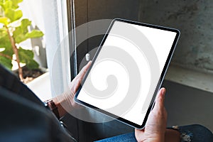 A woman holding black tablet pc with blank white screen in cafe