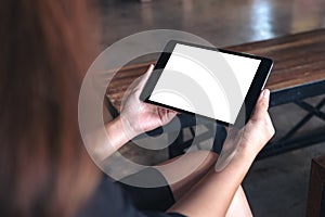 A woman holding black tablet pc with white blank desktop screen in cafe