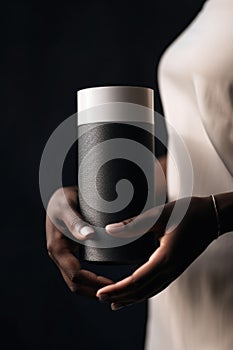 A woman holding a black and white speaker in her hands. AI generative image.