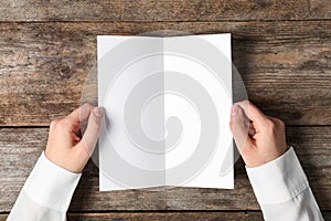 Woman holding blank brochure mock up on wooden table