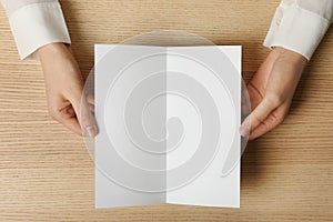 Woman holding blank brochure mock up on wooden table