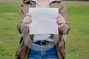 woman holding a blank white sheet of paper on her outstretched hand. place to write. paper
