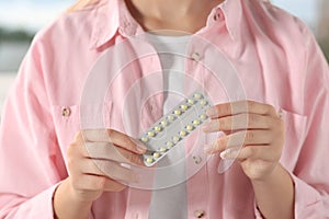 Woman holding blister of oral contraception pills, closeup