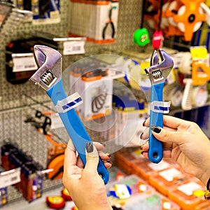 Woman holding a blue adjustable wrench at the store