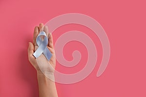 Woman holding blue ribbon on color background. Prostate cancer awareness concept