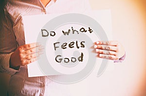 Woman holding board with the phrase do what feels good written on it. retro filtered image