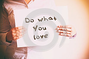 Woman holding board with the phrase do what you love written on it. retro filtered image