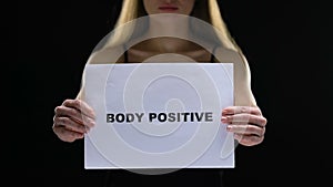 Woman holding body positive sign struggling against social standards and shaming