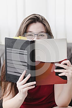 Woman holding a book in front of her with just the eyes out of t photo