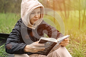 The woman is holding a book in her hands. Reading in the park, in the forest. Rest, training, relaxation concept