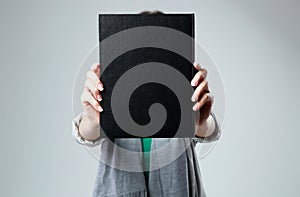 Woman holding a book and showing blank black cover