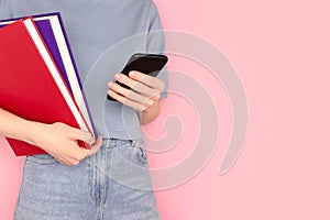 Woman holding books in her hands and use smartphone.