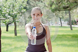 Woman holding a bottle of cold water in green park