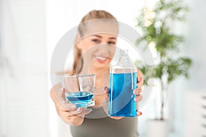 Woman holding bottle and glass with mouthwash