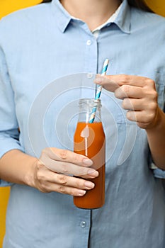 Woman holding bottle of tasty carrot juice