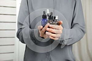 Woman holding bottles with essential oils on blurred background