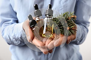 Woman holding bottles of essential oils and fir branches