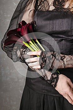 Woman holding bouquet of black calla flowers (Zantedeschia)