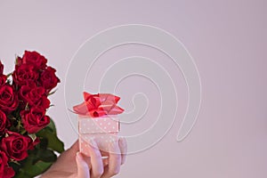 Woman holding a bouquet of red roses and a gift