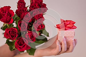 Woman holding a bouquet of red roses and a gift