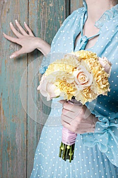 Woman holding bouquet of yellow carnation and pink roses