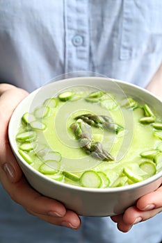 Woman holding bowl with delicious asparagus soup, closeup