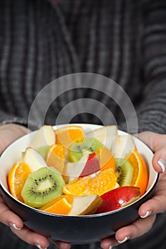 Woman holding bowl of fresh fruit