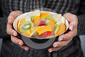 Woman holding bowl of fresh fruit