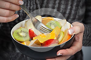 Woman holding bowl of fresh fruit