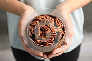 Woman holding bowl with shelled pecan nuts in hands