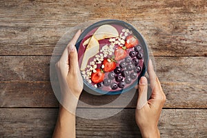 Woman holding bowl of tasty acai smoothie