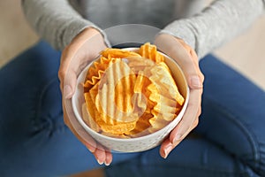 Woman holding bowl with tasty potato chips, closeup