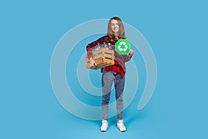 Woman holding box with empty plastic bottles and green recycling sign, fights environmental issues.