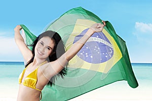 woman holding brazilian flag on seaside