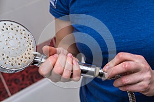 Woman is holding a broken shower sprinkler head in her hands and changes to a new one