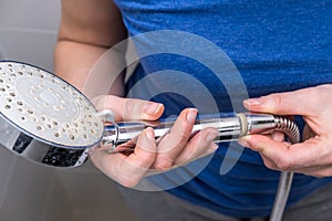 Woman is holding a broken shower sprinkler head in her hands and changes to a new one