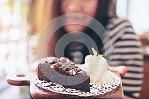 Woman holding brownie cake and whipped cream with feeling happy and good lifestyle in the modern cafe