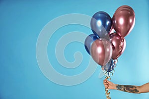 Woman holding bunch of balloons on color background