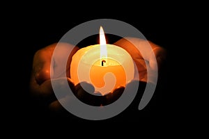 Woman holding burning candle on dark background