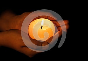 Woman holding burning candle on dark background