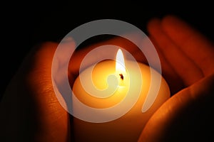 Woman holding burning candle in darkness,